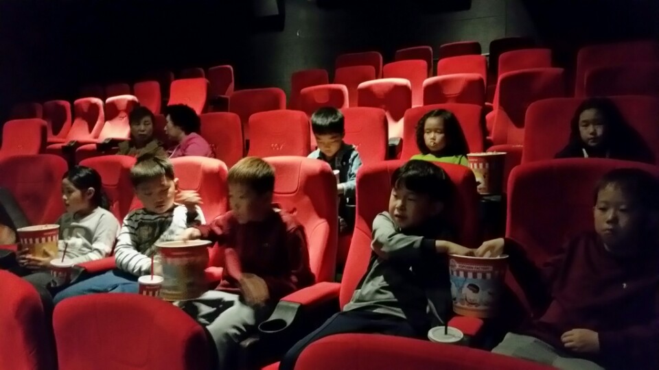 영화관에 앉아 영화 볼 준비를 하는 아이들